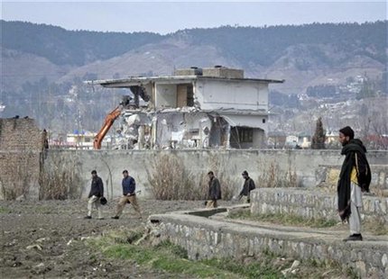 Policemen walk past while demolition work is carried out on the building where al Qaeda leader Osama bin Laden was killed by U.S. special fo Policemen walk past while demolition work is carried out on the building where al Qaeda leader Osama bin Laden was killed by U.S. special fo