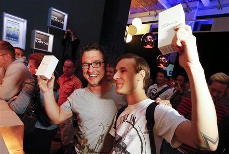Customers pose for the media after they were first in line to buy Samsung Electronics' new Samsung Galaxy SIII smartphones during a late nig Customers pose for the media after they were first in line to buy Samsung Electronics' new Samsung Galaxy SIII smartphones during a late nig