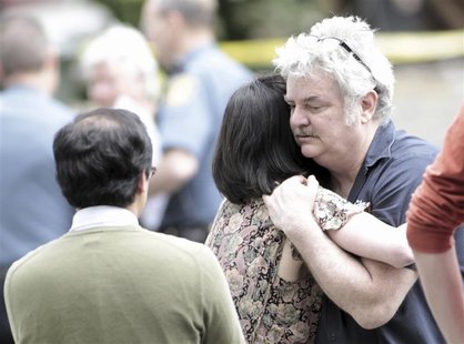 The owner (R) of a coffee shop, where a gunman shot and killed three people and injured two more, is consoled by a woman in Seattle, Washing The owner (R) of a coffee shop, where a gunman shot and killed three people and injured two more, is consoled by a woman in Seattle, Washing