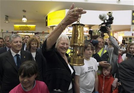 Dame Mary Peters carries the Olympic flame through Belfast City Airport after its arrival from the Isle Of Man June 2, 2012. REUTERS/Cathal Dame Mary Peters carries the Olympic flame through Belfast City Airport after its arrival from the Isle Of Man June 2, 2012. REUTERS/Cathal