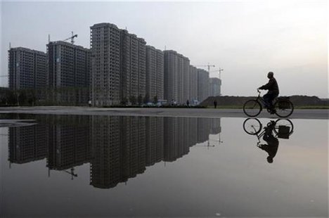 A man cycles past a residential complex under construction, which is reflected in a puddle, in Taiyuan, Shanxi province June 3, 2012. REUTER A man cycles past a residential complex under construction, which is reflected in a puddle, in Taiyuan, Shanxi province June 3, 2012. REUTER