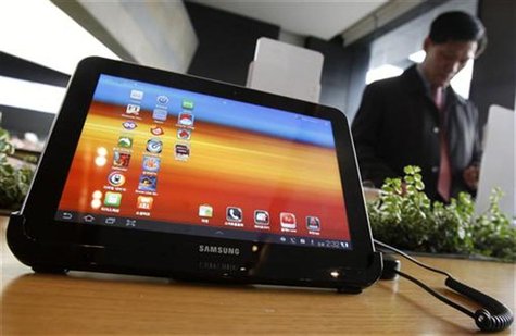 A visitor looks around behind Samsung Electronics' Galaxy Tab 10.1 tablet displayed for customers at a registration desk at South Korean mob A visitor looks around behind Samsung Electronics' Galaxy Tab 10.1 tablet displayed for customers at a registration desk at South Korean mob