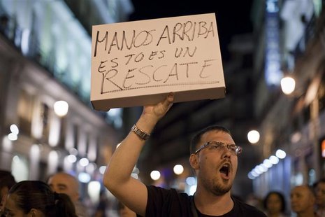 A protester holds up a sign, which reads: "Hands up, this is a rescue", in reference to Spain's bailout, in Puerta del Sol square in Madrid, A protester holds up a sign, which reads: "Hands up, this is a rescue", in reference to Spain's bailout, in Puerta del Sol square in Madrid,