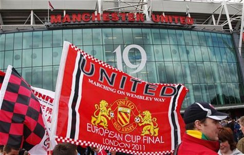 Manchester United supporters wave flags outside the stadium before their English Premier League soccer match against Blackpool at Old Traffo Manchester United supporters wave flags outside the stadium before their English Premier League soccer match against Blackpool at Old Traffo