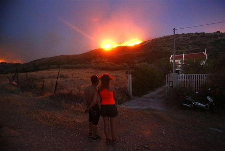 Locals look at a forest fire approaching their house at Thymari coastal village, 40 km (25 miles) southeast of Athens, June 16, 2012. REUTER Locals look at a forest fire approaching their house at Thymari coastal village, 40 km (25 miles) southeast of Athens, June 16, 2012. REUTER