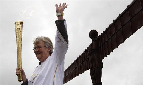 Torch bearer Iris Hutchinson waves while holding a London 2012 Olympic Games torch at the Angel of the North sculpture near Gateshead, north Torch bearer Iris Hutchinson waves while holding a London 2012 Olympic Games torch at the Angel of the North sculpture near Gateshead, north
