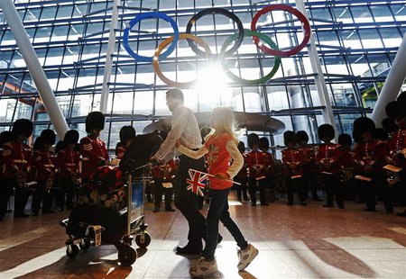 Travellers pass the Olympic Rings during an unveiling ceremony in the Terminal Five arrivals hall at Heathrow Airport, in preparation for th Travellers pass the Olympic Rings during an unveiling ceremony in the Terminal Five arrivals hall at Heathrow Airport, in preparation for th