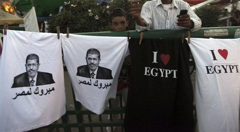 A boy stands near t-shirts with images of elected president Mohamed Mursi and words that read "Congratulations to Egypt" that are sold durin A boy stands near t-shirts with images of elected president Mohamed Mursi and words that read "Congratulations to Egypt" that are sold durin