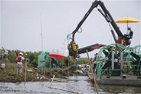 Workers remove oil soaked grass from a marshland, one year after the BP Oil Spill, in Bay Jimmy near Myrtle Grove, Louisiana April 20, 2011. Workers remove oil soaked grass from a marshland, one year after the BP Oil Spill, in Bay Jimmy near Myrtle Grove, Louisiana April 20, 2011.