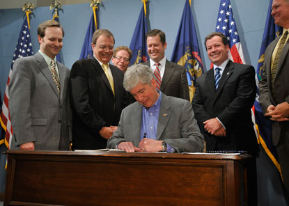 Gov. Rick Snyder signs a state income tax into law Friday, as Republican lawmakers look on. Gov. Rick Snyder signs a state income tax into law Friday, as Republican lawmakers look on.