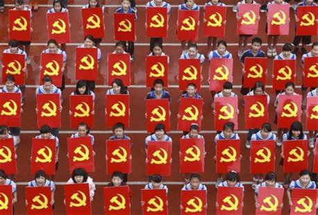 Middle school students hold cardboards featuring the emblems of the Communist Party of China as they pose for photographs during an event to Middle school students hold cardboards featuring the emblems of the Communist Party of China as they pose for photographs during an event to