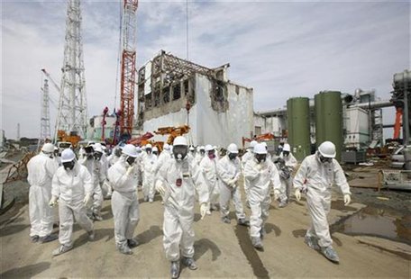 Members of the media and Tokyo Electric Power Co. (TEPCO) employees, wearing protective suits and masks, walk in front of the No. 4 reactor Members of the media and Tokyo Electric Power Co. (TEPCO) employees, wearing protective suits and masks, walk in front of the No. 4 reactor
