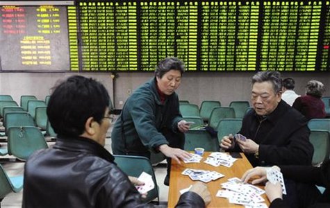Investors play cards in front of an electronic board showing stock information filled with green-coloured figures, which indicate falling pr Investors play cards in front of an electronic board showing stock information filled with green-coloured figures, which indicate falling pr