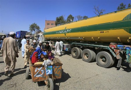 Men push a family past a fuel tanker, carrying supplies for NATO Forces, at the Pakistan-Afghan border of Torkham October 10, 2010. REUTERS/ Men push a family past a fuel tanker, carrying supplies for NATO Forces, at the Pakistan-Afghan border of Torkham October 10, 2010. REUTERS/