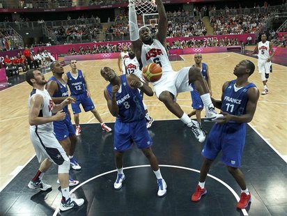 Lebron James of the U.S. hangs on the rim as France's Ali Traore (L) and Florent Pietrus (R) look on during their men's Group A basketball m Lebron James of the U.S. hangs on the rim as France's Ali Traore (L) and Florent Pietrus (R) look on during their men's Group A basketball m