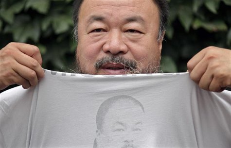 Chinese dissident artist Ai Weiwei pulls up his shirt bearing a portrait of himself as he chats with journalists at the courtyard of his stu Chinese dissident artist Ai Weiwei pulls up his shirt bearing a portrait of himself as he chats with journalists at the courtyard of his stu