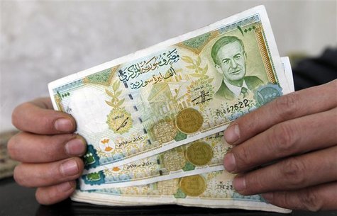 A money changer holds one thousand Syrian pound banknotes, with the picture of late Syrian President Hafez al-Assad, in the border city of K A money changer holds one thousand Syrian pound banknotes, with the picture of late Syrian President Hafez al-Assad, in the border city of K