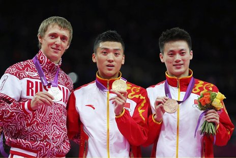 Dong Dong of China celebrates with his gold medal next to silver medallist Dmitry Ushakov (L) and bronze medallist Lu Chunlong (R) at the me Dong Dong of China celebrates with his gold medal next to silver medallist Dmitry Ushakov (L) and bronze medallist Lu Chunlong (R) at the me