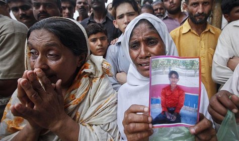 A woman holds a portrait of her son while waiting with others to identify his body, after a fire at a garment factory in Karachi September 1 A woman holds a portrait of her son while waiting with others to identify his body, after a fire at a garment factory in Karachi September 1