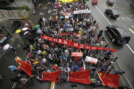 Demonstrators with banners and Chinese national flags march along the main road during a protest against Japan's decision to purchase disput Demonstrators with banners and Chinese national flags march along the main road during a protest against Japan's decision to purchase disput