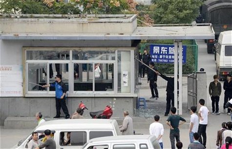Workers clean up glass shards from the broken windows of a security room near paramilitary police vehicles parked near an entrance of a Foxc Workers clean up glass shards from the broken windows of a security room near paramilitary police vehicles parked near an entrance of a Foxc