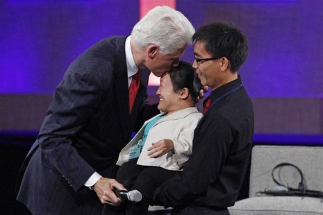 Former U.S. President Bill Clinton kisses Chen Li (C), a disabled woman who has opened a school for the disabled in China, on the head at th Former U.S. President Bill Clinton kisses Chen Li (C), a disabled woman who has opened a school for the disabled in China, on the head at th