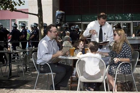 A family is served drinks at a restaurant while Occupy Wall Street activists protest through the streets of New York's Financial District on A family is served drinks at a restaurant while Occupy Wall Street activists protest through the streets of New York's Financial District on
