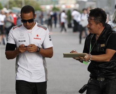 A fan asks McLaren Formula One driver Lewis Hamilton of Britain for an autograph as he walks in the paddock after the second practice sessio A fan asks McLaren Formula One driver Lewis Hamilton of Britain for an autograph as he walks in the paddock after the second practice sessio