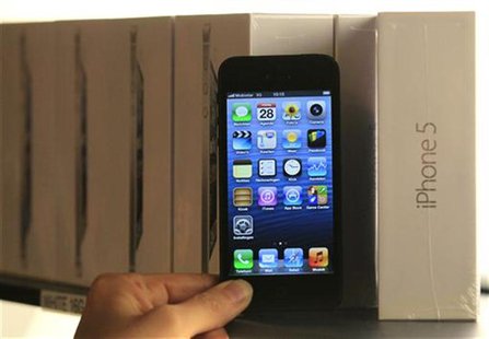 A customer holds up an Apple iPhone 5 to pose for a photo during an exclusive sale by Belgian operator Mobistar in Brussels September 28, 20 A customer holds up an Apple iPhone 5 to pose for a photo during an exclusive sale by Belgian operator Mobistar in Brussels September 28, 20