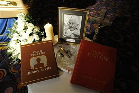 A tribute is seen next to the coffin of British entertainer Jimmy Saville as it is displayed to the public at The Queens Hotel in Leeds, nor A tribute is seen next to the coffin of British entertainer Jimmy Saville as it is displayed to the public at The Queens Hotel in Leeds, nor