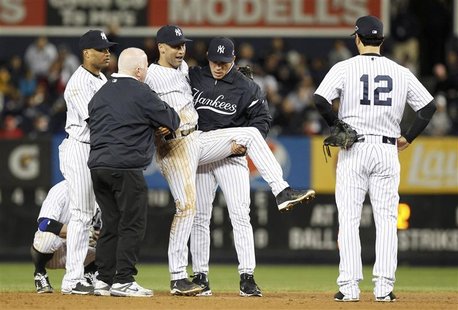 New York Yankees third baseman Eric Chavez (12) looks on as shortstop Derek Jeter is carried off the field by trainer Steve Donohue (2nd fro New York Yankees third baseman Eric Chavez (12) looks on as shortstop Derek Jeter is carried off the field by trainer Steve Donohue (2nd fro