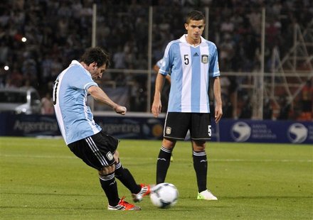 Argentina's Lionel Messi (L) kicks the ball to score his second goal against Uruguay as his teammate Fernando Gago looks on during their 201 Argentina's Lionel Messi (L) kicks the ball to score his second goal against Uruguay as his teammate Fernando Gago looks on during their 201