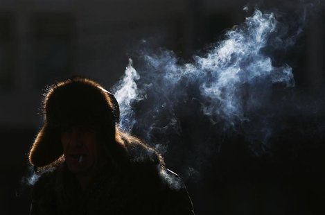 A man smokes a cigarette as he walks through a shaft of sunlight in temperatures, about minus 15 degrees Celsius (5 degrees Fahrenheit) in c A man smokes a cigarette as he walks through a shaft of sunlight in temperatures, about minus 15 degrees Celsius (5 degrees Fahrenheit) in c