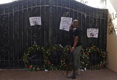 A Libyan government militia guarding the main entrance of the U.S. consulate that was attacked last week, fixes a note written by Libyans ag A Libyan government militia guarding the main entrance of the U.S. consulate that was attacked last week, fixes a note written by Libyans ag