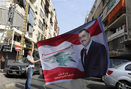 A Sunni Muslim man hangs up a poster with an image of senior intelligence official Wissam al-Hassan, in the Tariq al-Jadideh district in Bei A Sunni Muslim man hangs up a poster with an image of senior intelligence official Wissam al-Hassan, in the Tariq al-Jadideh district in Bei