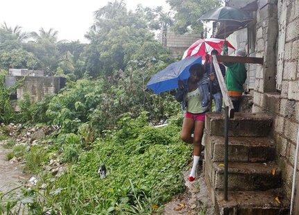 Jamaicans shelter themselves from the rain of approaching Hurricane Sandy as they walk along Sandy Park Gully in Kingston October 24, 2012. Jamaicans shelter themselves from the rain of approaching Hurricane Sandy as they walk along Sandy Park Gully in Kingston October 24, 2012.