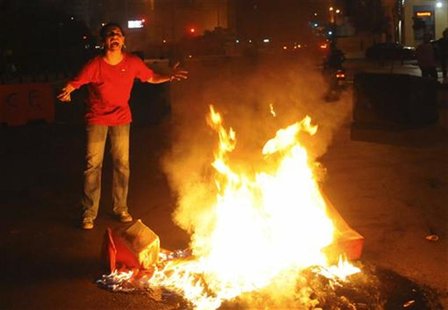 A Sunni Muslim woman reacts as she burns a tire, blocking a street in Beirut during protests against the killing of senior intelligence offi A Sunni Muslim woman reacts as she burns a tire, blocking a street in Beirut during protests against the killing of senior intelligence offi