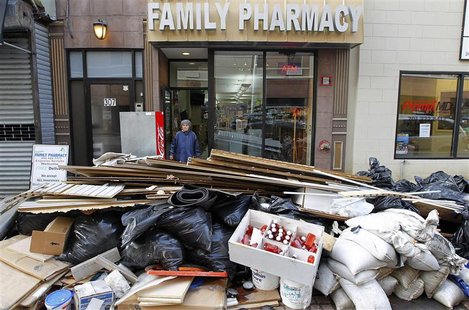 A woman leaves a pharmacy damaged by floodwaters as debris is pilled in the streets in Hoboken, New Jersey, November 2, 2012. REUTERS/Gary H A woman leaves a pharmacy damaged by floodwaters as debris is pilled in the streets in Hoboken, New Jersey, November 2, 2012. REUTERS/Gary H