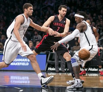Toronto Raptors center Andrea Bargnani (7) tries to pass between Brooklyn Nets center Brook Lopez (L) and forward Gerald Wallace (R) in the Toronto Raptors center Andrea Bargnani (7) tries to pass between Brooklyn Nets center Brook Lopez (L) and forward Gerald Wallace (R) in the