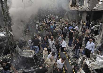 A crowd gathers in front of a building and car damaged after a bomb explosion in the Mezzeh 86 area in Damascus, in this handout photograph A crowd gathers in front of a building and car damaged after a bomb explosion in the Mezzeh 86 area in Damascus, in this handout photograph