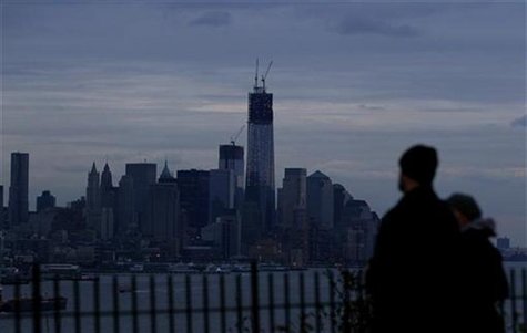A couple look out at the skyline of New York with most of Lower Manhattan remaining in the dark as they stand in a park along the Hudson Riv A couple look out at the skyline of New York with most of Lower Manhattan remaining in the dark as they stand in a park along the Hudson Riv