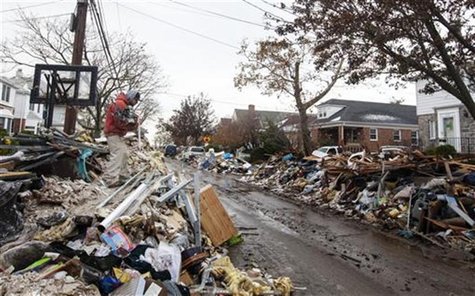 A worker deposits steel onto the top of a pile of debris stacked up outside of homes damaged from flooding that inundated the area during hu A worker deposits steel onto the top of a pile of debris stacked up outside of homes damaged from flooding that inundated the area during hu