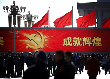 People walk in front of a large screen displaying propaganda slogans on Beijing's Tiananmen Square November 12, 2012. REUTERS/David Gray People walk in front of a large screen displaying propaganda slogans on Beijing's Tiananmen Square November 12, 2012. REUTERS/David Gray