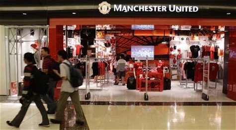 Shoppers walk past a Manchester United merchandise store at a mall in Singapore June 14, 2012. REUTERS/Tim Chong Shoppers walk past a Manchester United merchandise store at a mall in Singapore June 14, 2012. REUTERS/Tim Chong