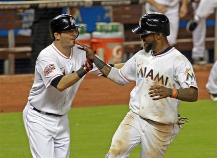 Miami Marlins shortstop Jose Reyes (R) celebrates with teammate Gil Velazquez after Reyes scored the winning run over the New York Mets on a Miami Marlins shortstop Jose Reyes (R) celebrates with teammate Gil Velazquez after Reyes scored the winning run over the New York Mets on a
