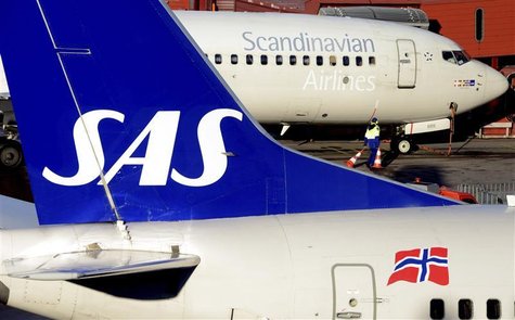 A ground staffer carries warning cones between two SAS Boeing 737 aircrafts parked at Arlanda airport's Terminal Five, north of Stockholm No A ground staffer carries warning cones between two SAS Boeing 737 aircrafts parked at Arlanda airport's Terminal Five, north of Stockholm No