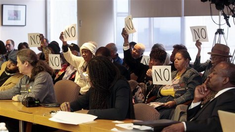 City of Detroit activists hold up protest signs to encourage the Detroit City Council members to vote no on a contract to hire a firm to hel City of Detroit activists hold up protest signs to encourage the Detroit City Council members to vote no on a contract to hire a firm to hel