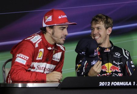 Red Bull Formula One driver Sebastian Vettel (R) of Germany offers his cap to Ferrari Formula One driver Fernando Alonso of Spain during a n Red Bull Formula One driver Sebastian Vettel (R) of Germany offers his cap to Ferrari Formula One driver Fernando Alonso of Spain during a n