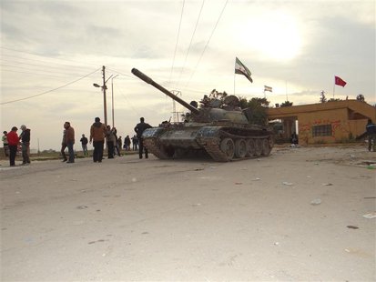 Residents and Free Syrian Army fighters pose near a tank after the fighters said they fought and defeated government troops from the town of Residents and Free Syrian Army fighters pose near a tank after the fighters said they fought and defeated government troops from the town of