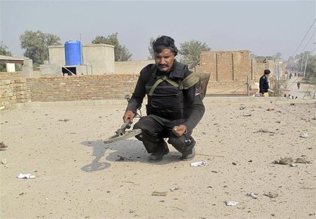 A security officer collects evidence on the roof of a house after a roadside bomb during a Shi'ite procession in Dera Ismail Khan, in Pakist A security officer collects evidence on the roof of a house after a roadside bomb during a Shi'ite procession in Dera Ismail Khan, in Pakist